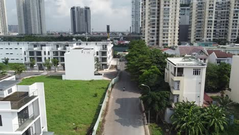 aerial reverse dolly rises above empty road and condo apartment buildings in vietnam