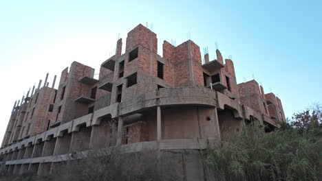abandoned multi-story building surrounded by overgrown vegetation in varosha on a sunny day