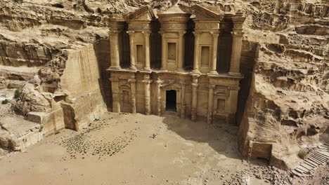 aerial view around a person walking in front of the el-deir monastery, in sunny jordan