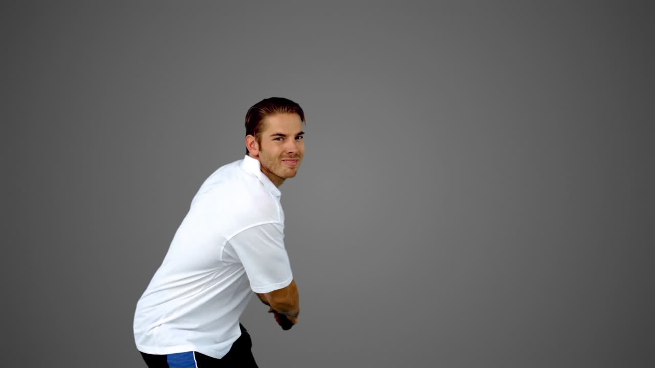 Attractive man playing tennis on grey screen