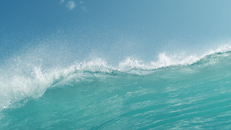 Turquoise wave crests beneath clear blue sky in clean, seamless loop aesthetic