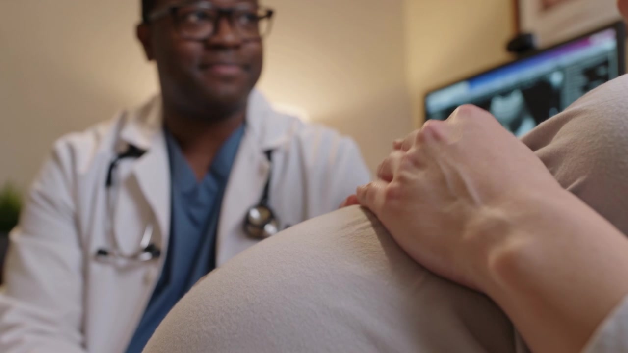 Reacting to doctor speaking in lab coat, pregnant woman rubbing abdomen over top for checkup, scan