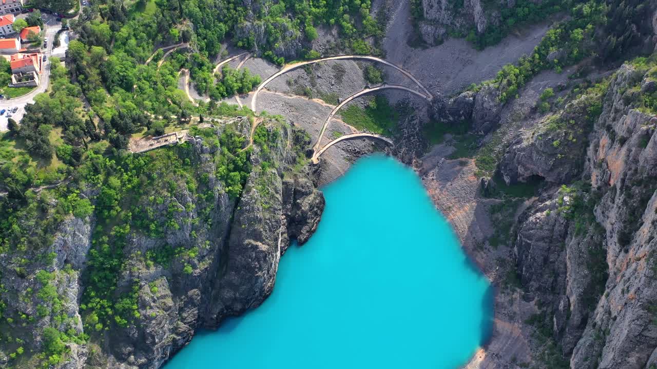 Aerial of colorful Blue Lake surrounded by tall stone walls near Imotski, Croatia