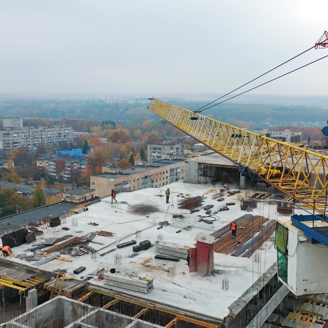 Aerial view of construction site in the city. Big crane and workers on the roof. Construction of new apartment building in progress.