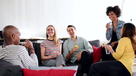 friends laughing over drinks at a loft apartment, close up