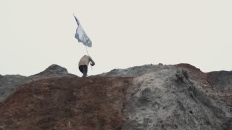 man with black flag on mountaintop