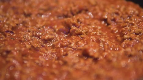 close up of cooking sauce bolognese with minced meat boiling in pan