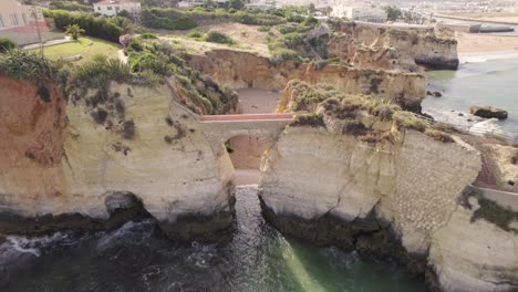 retroceso aéreo sobre el puente de arco en praia dos estudantes en lagos, algarve
