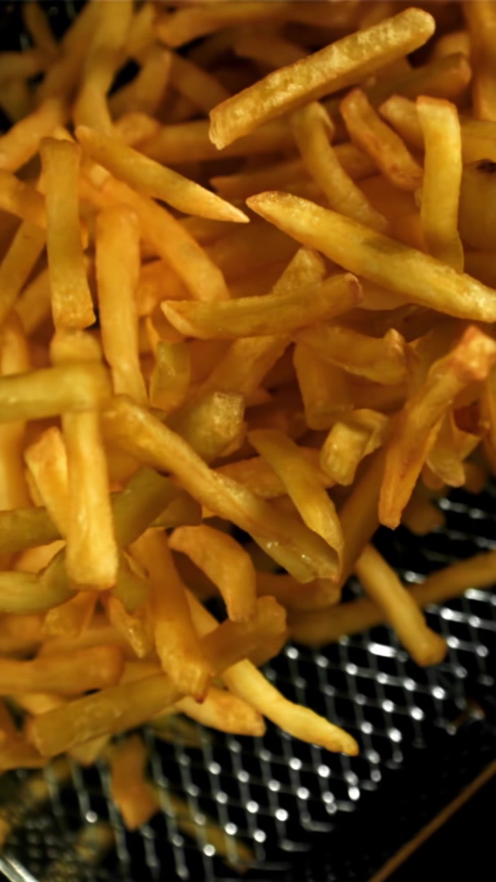 Nyfriterade gyllenbruna pommes frites i en frityrkorg