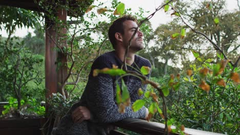 thoughtful caucasian man standing on balcony admiring the countryside view