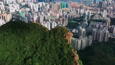 Kowloon-landmark-Lion-rock-mountain-peak-overlooking-downtown-Hong-Kong-skyscraper-business-district-aerial-orbit-right