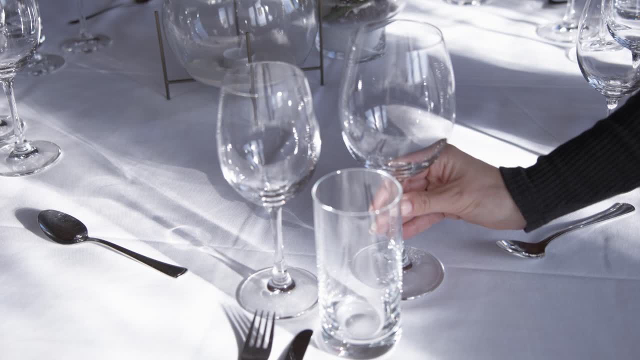 Waiter Placing Clean Wine Glass on Fine Dining Table with White Cloth