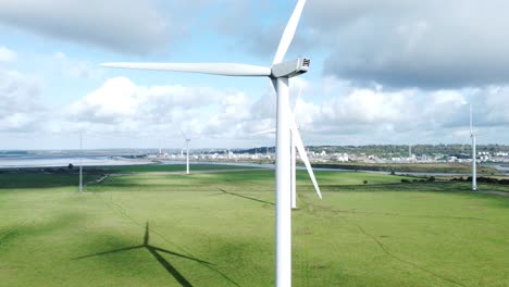 aerial view flying around renewable energy wind farm wind turbines spinning on british countryside orbit right slow