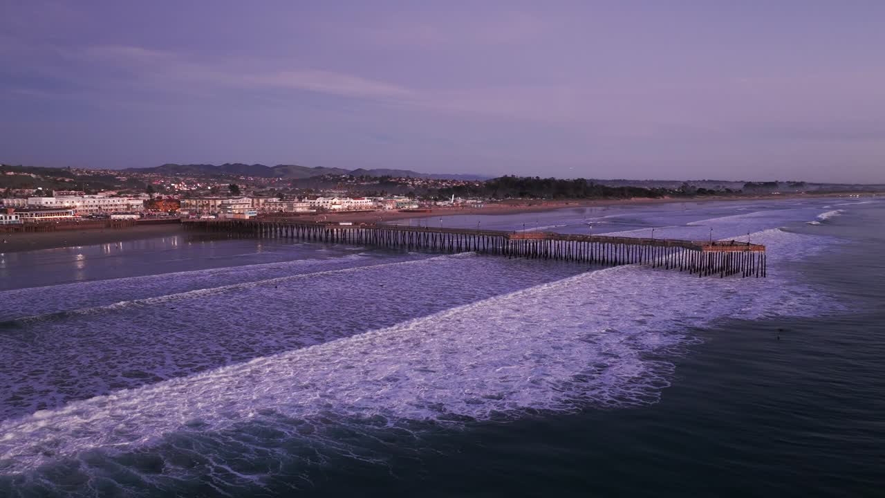 dramático disparo de avión no tripulado volando hacia el muelle de la playa de pismo durante la puesta de sol