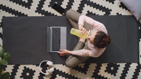 Mujer-Escribiendo-En-La-Computadora-Portátil-Y-Bebiendo-Agua-En-El-Piso-En-Casa