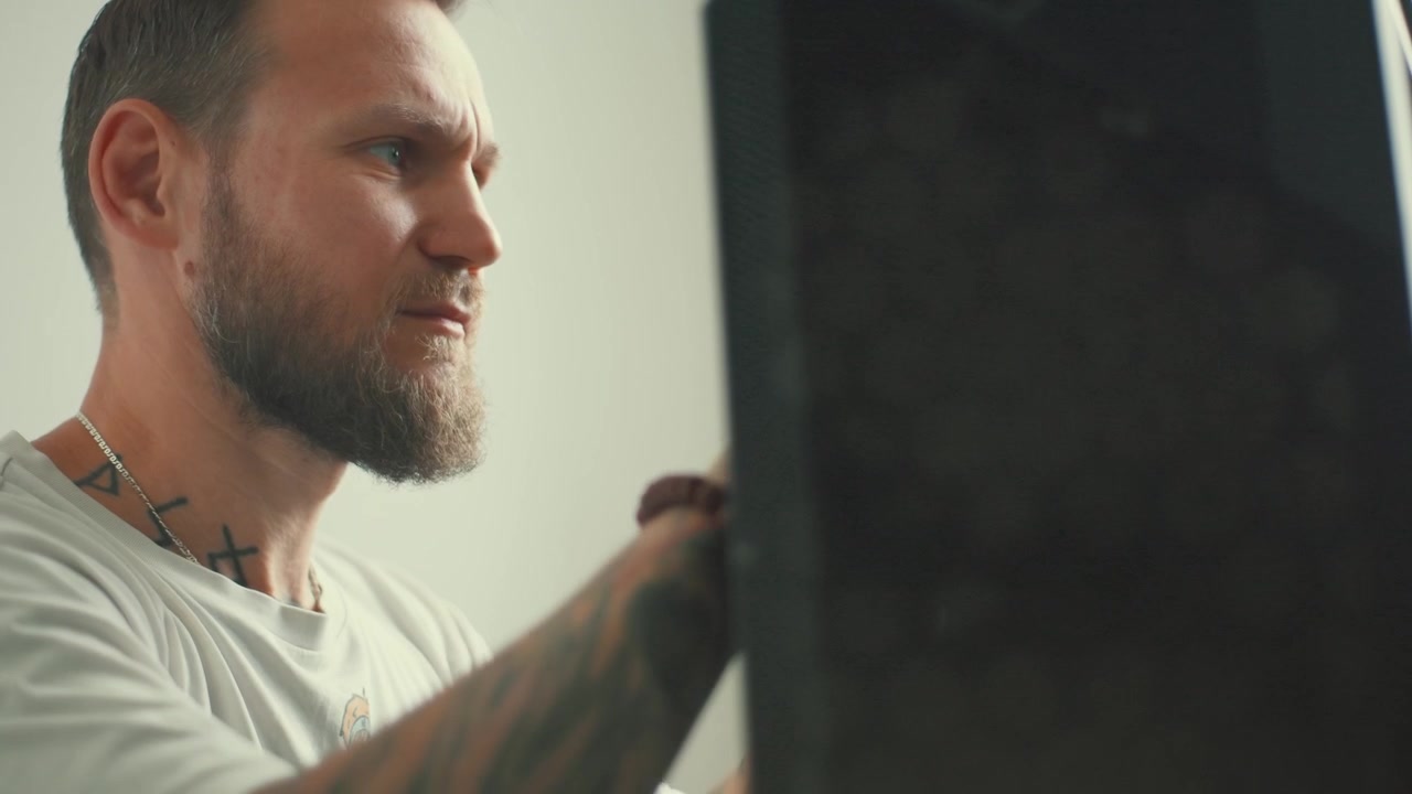 Man works on music equipment in a studio setting during the afternoon hours of the day