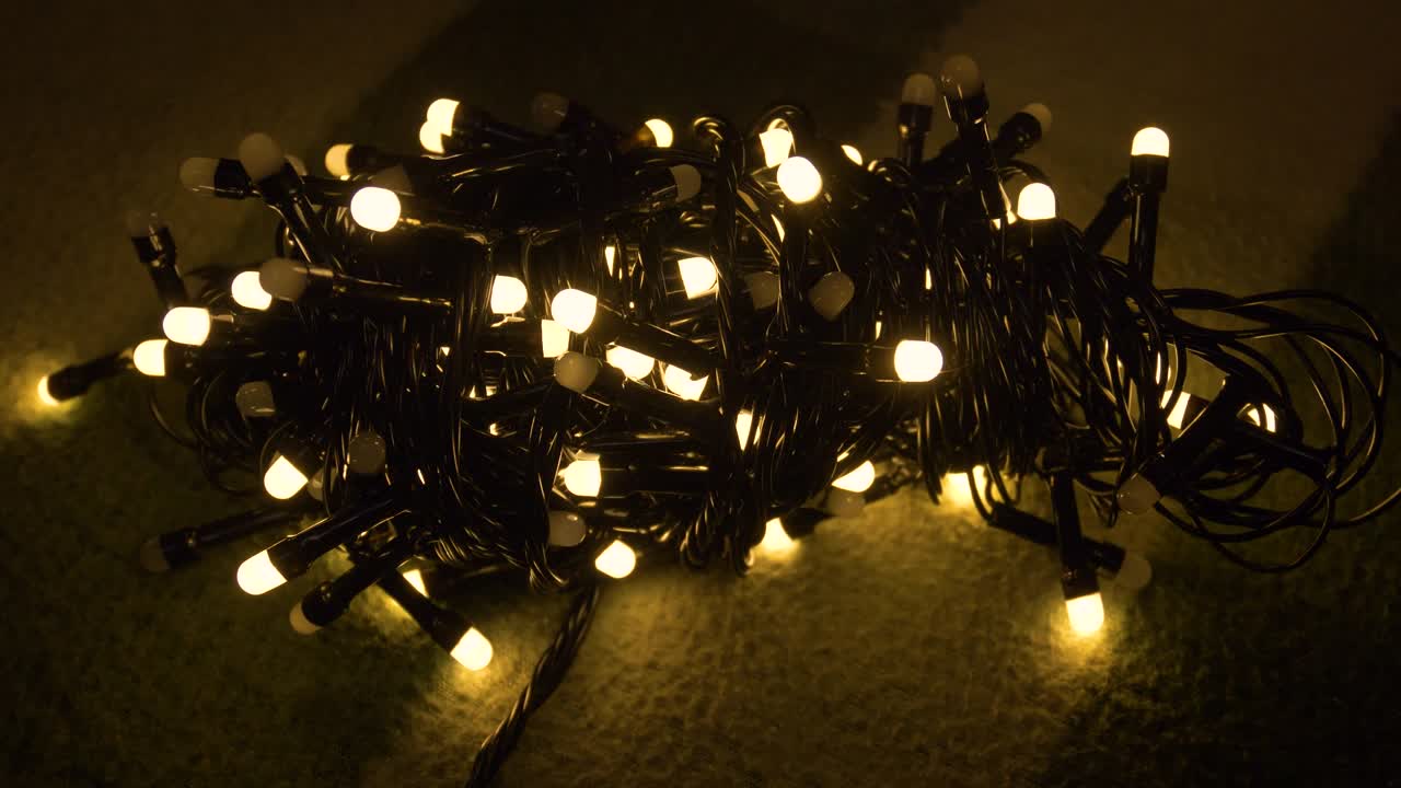 Nahaufnahme einer Weihnachtsgirlande mit goldenen Lichtern auf einem Plaid. Weihnachtskonzept. Wohndekoration