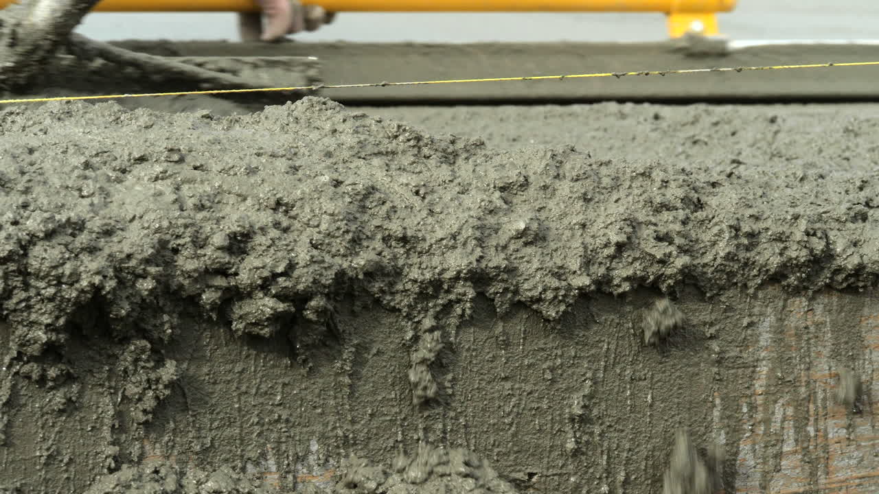 과도한 조잡한 젖은 시멘트가 새 집 슬래브 공사의 가장자리 위로 밀려났습니다.