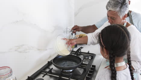 biracial grandmother and granddaughter cook together, pouring batter into a pan with copy space
