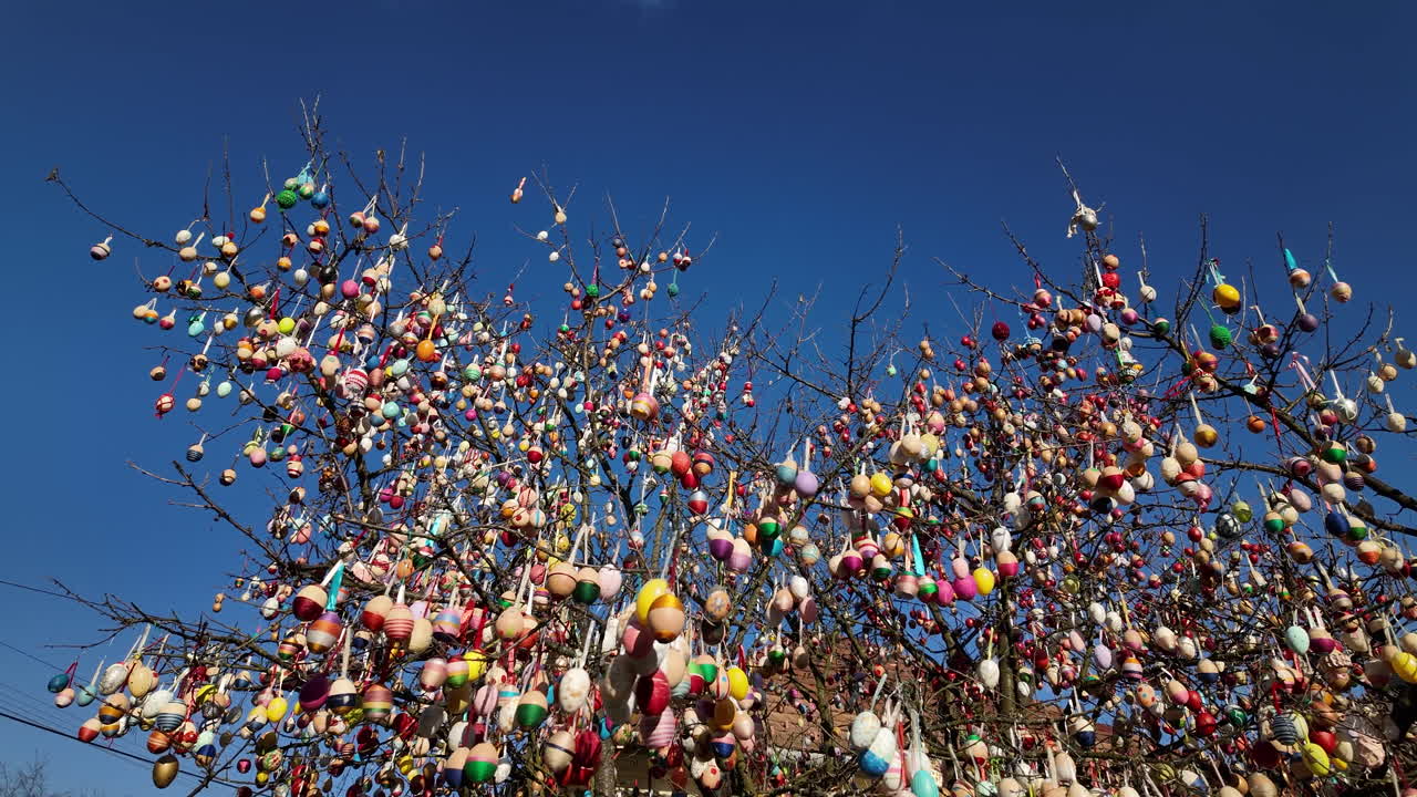 Easter egg tree with colorful ornaments under a blue sky
