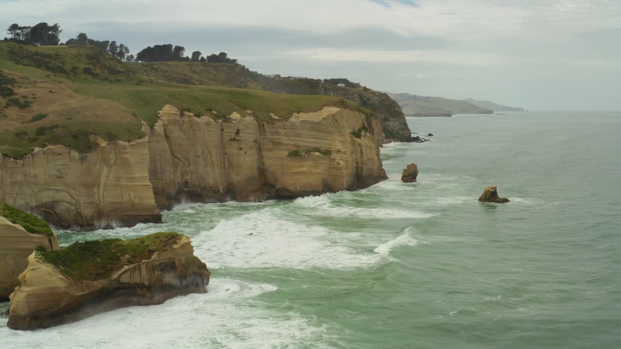Orbiting aerial shot of rock formations and cliffs along the coastline in New Zealand