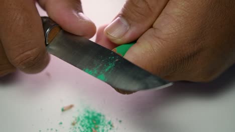 Footage-of-hands-slowly-sharpening-a-pencil-and-some-coloured-pencils-with-a-sharp-knife