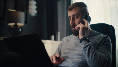 professional stock exchange trader monitoring real-time stocks and exchange market charts using laptop, talking on cellphone. successful investment agent working in cozy office of financial agency.