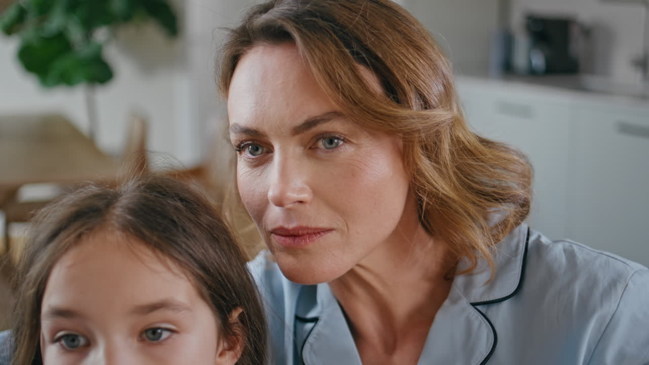 Interested mother watching movie with daughter portrait. Woman looking camera