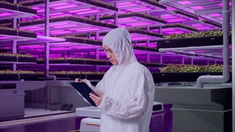 vertical farm worker examining plants and recording data.
