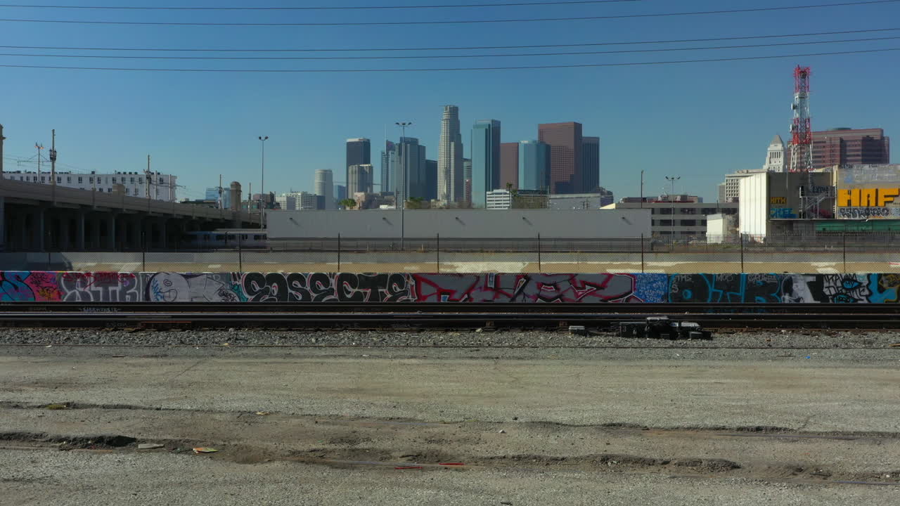 Flying over train tracks and the LA river to reveal the Downtown Los Angeles Skyline on a clear blue day, Drone, California USA