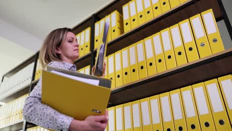 woman organizing files in an office with many yellow binders