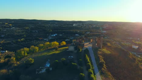 Toma-De-Drone-De-Un-Edificio-De-Capilla-Blanca-En-Una-Colina-Con-Muralla-Medieval-Y-Torre-En-Alentejo,-Portugal