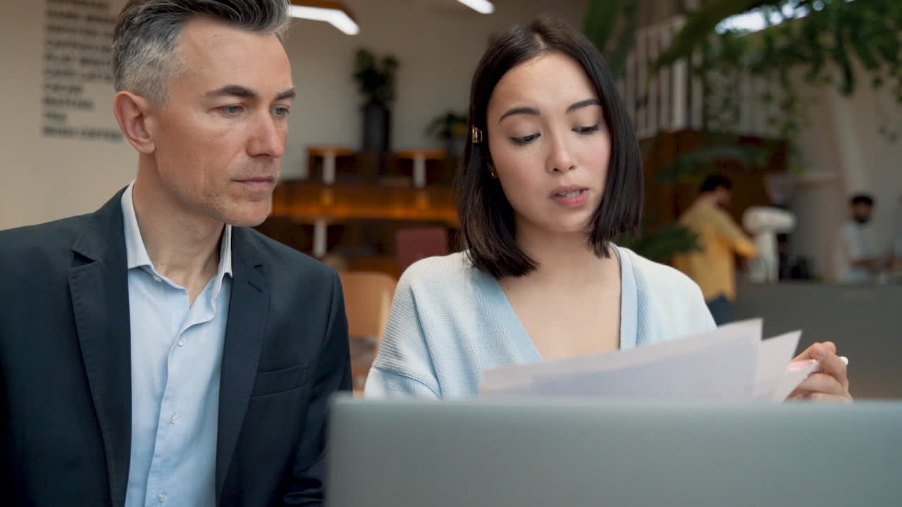 一位商人在咖啡店開會時向商人展示文件