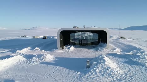 a stunning modern structure nestled in a vast snowy wilderness, showcasing innovative architecture blending design with the natural arctic environment