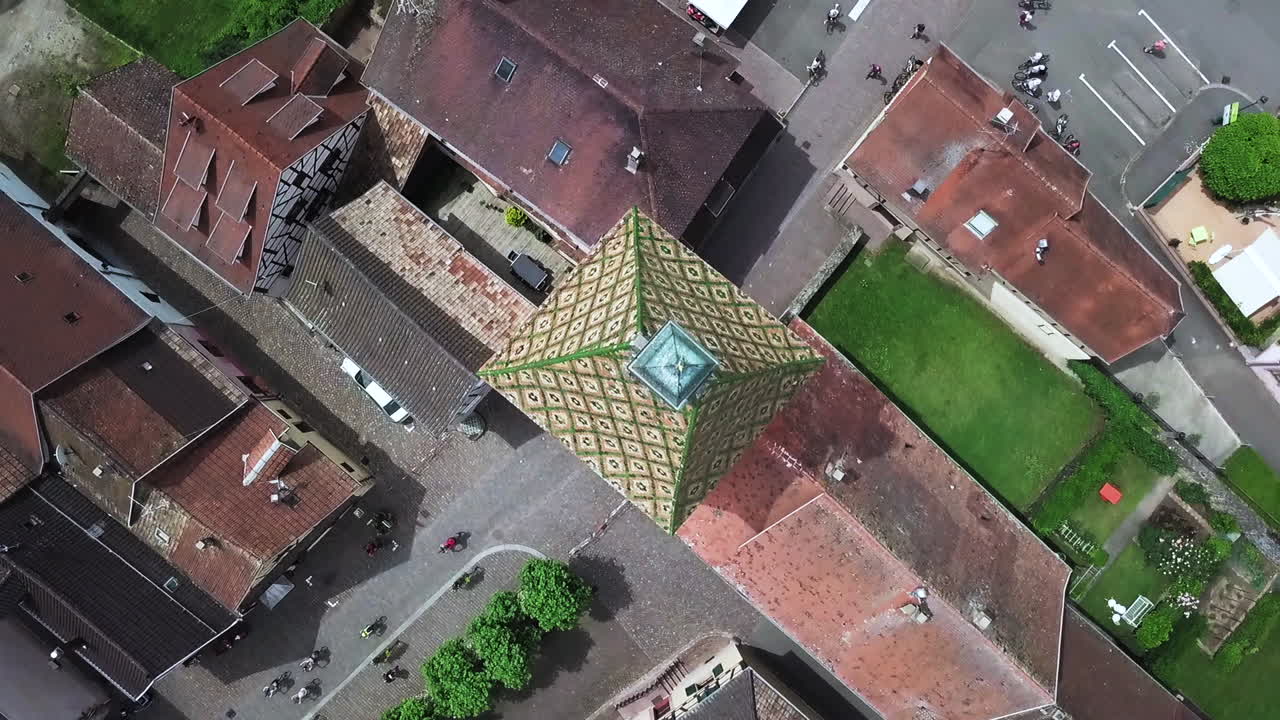마을 내에서 집과 이동하는 자전거 타는 사람을 보여주면서 시계탑 꼭대기에서 회전하는 탑뷰 공중 영상