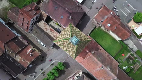 a pivoting top-view aerial footage on top of the clock tower while showing the houses and moving cyclists within the village