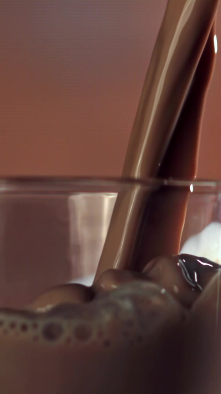 Versamento al rallentatore di latte al cioccolato in un bicchiere