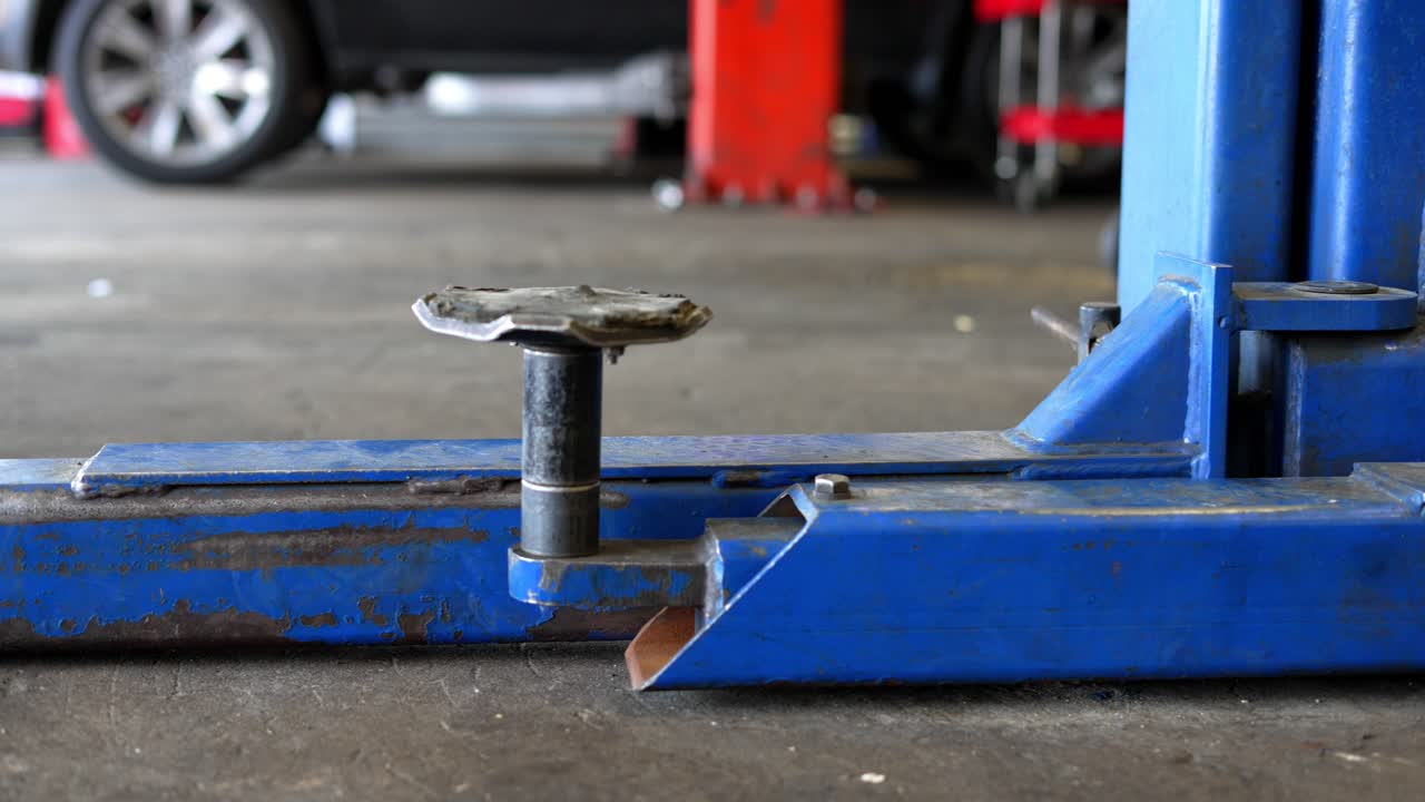 panorámica lenta de derecha a izquierda del gato elevador de camión de automóvil industrial azul angustiado en la tienda de garaje mecánico