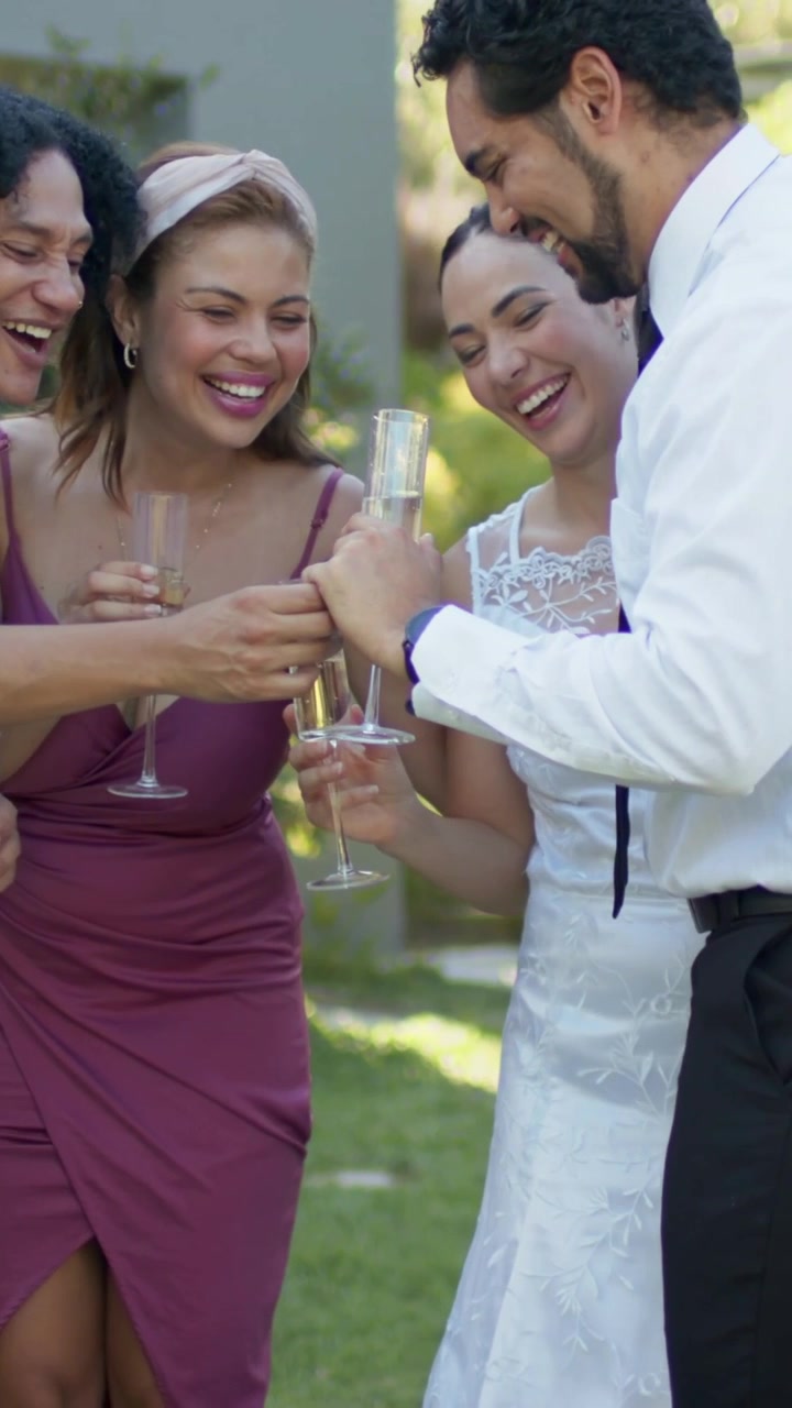 Vídeo vertical: Homem de camisa azul estendendo o braço, brindando com taças com amigos no jardim.
