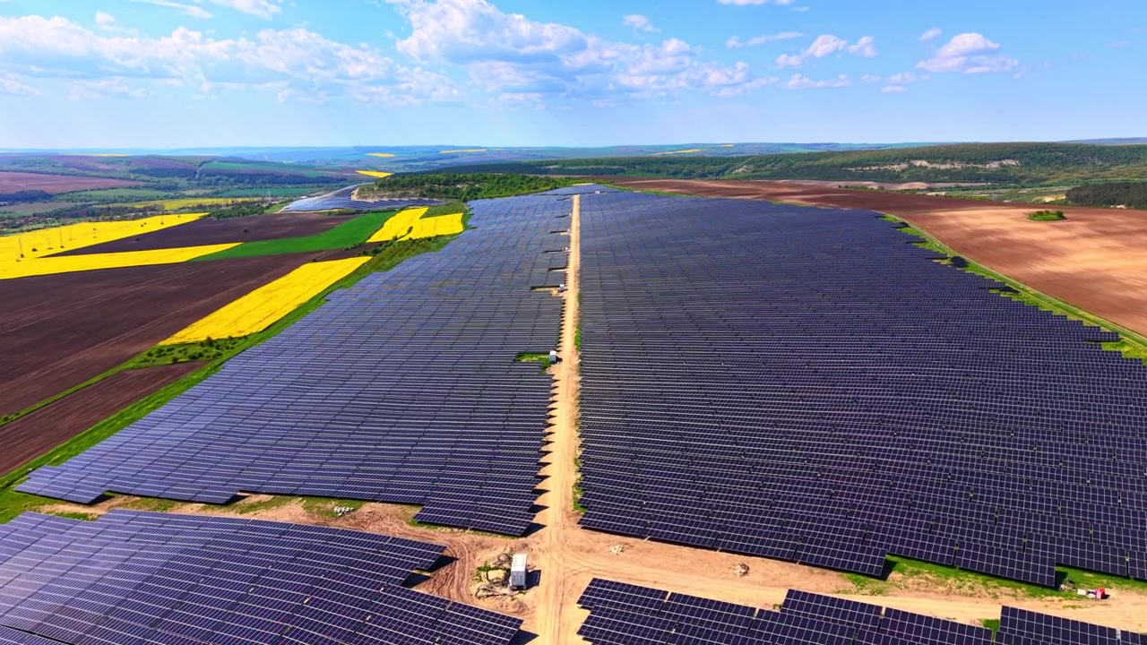 Stor solcellepark i landskab. Luftfoto af omfattende solcelleanlæg placeret mellem landbrugsmarker under en klar himmel