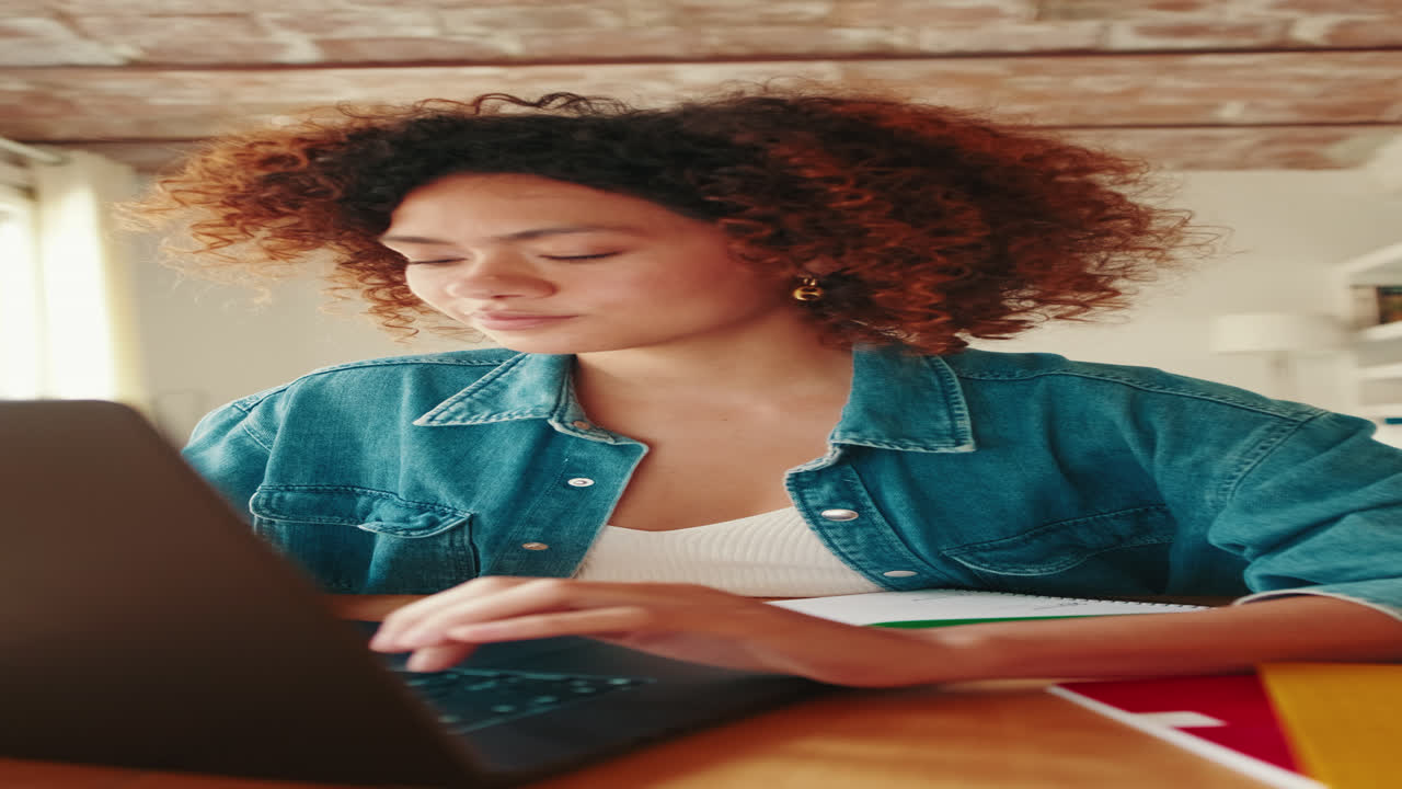 Young Woman Typing on Laptop While Working from Home