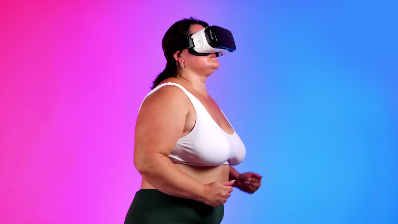 Woman with overweight in a tracksuit and VR headset doing exercises in a studio with blue and red background