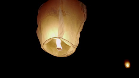 close-up of a glowing sky lantern floating in the dark night sky