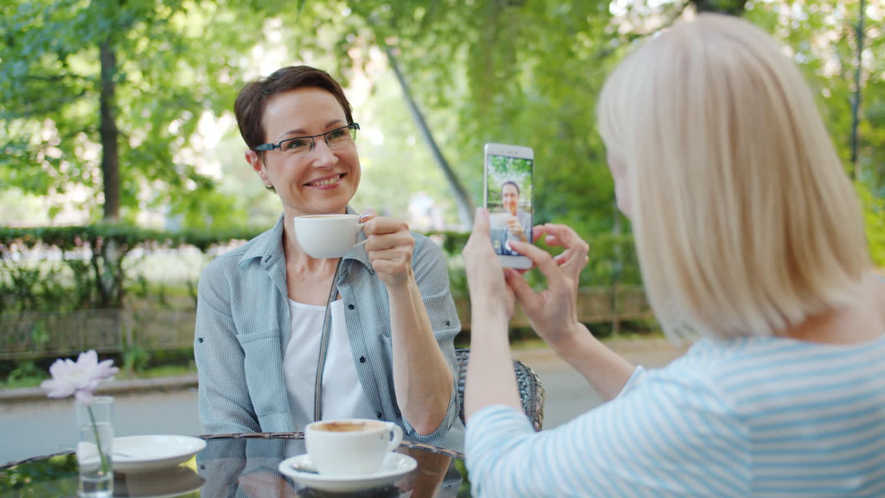 Two women friends taking a photo in a cafe