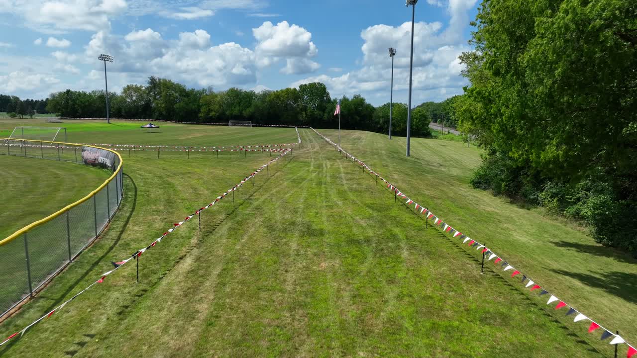 Start line of cross country course in America&mdash;aerial flight over race course with American flag waving on high school campus on bright day