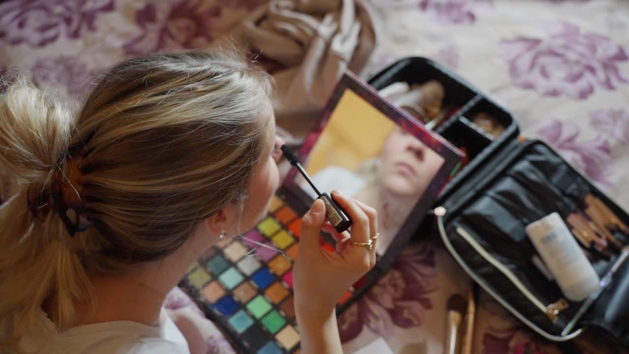 Bride applying makeup in front of a mirror with her colorful eyeshadow palette