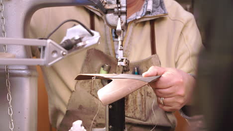 bespoke shoemaker stitching together leather pieces for shoe