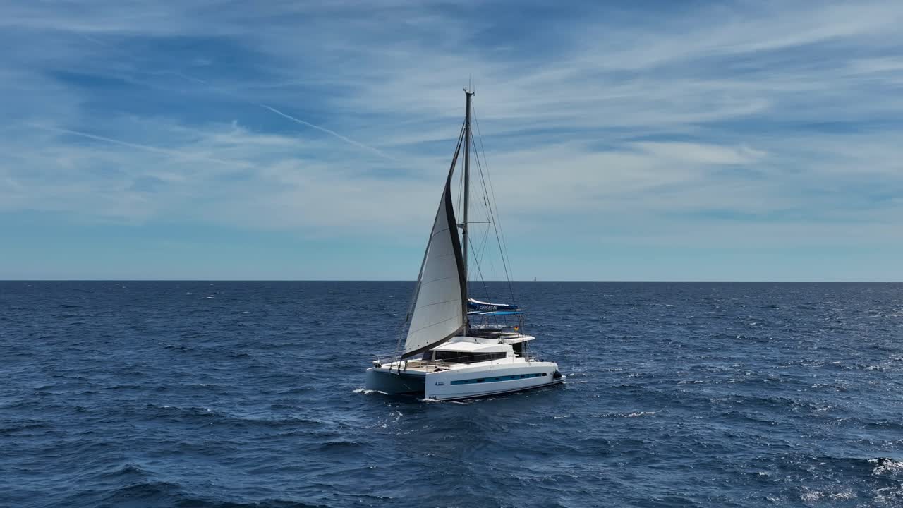 Ripresa aerea al rallentatore con drone di un catamarano a vela sul mare Mediterraneo blu a Maiorca