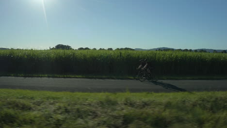 Tracking-shot-of-two-cyclists-on-a-countryside-road-in-summer