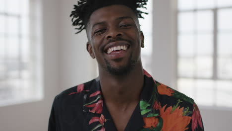 retrato en primer plano de un hombre afroamericano relajado riendo alegremente mirando a la cámara disfrutando del cambio de estilo de vida usando una camisa hawaiana en un nuevo apartamento